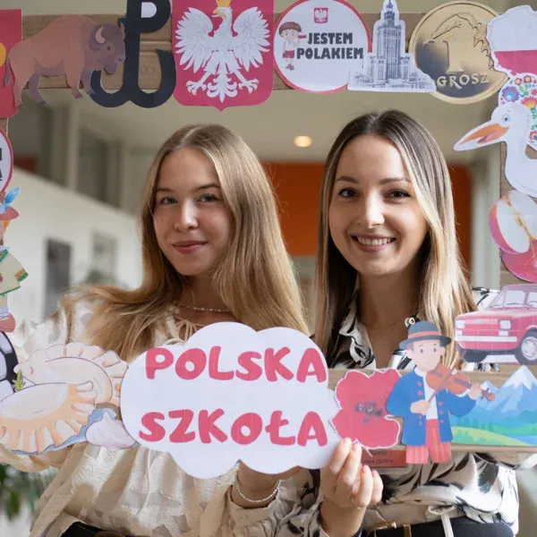 Dwie osoby prezentujące dekorację z napisem „Polska szkoła”